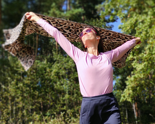 Frau in einem rosa Shirt tanzt mit einem Leopardentuch und nutzt Traumreisen/Fantasiereisen als Entspannungsübung.